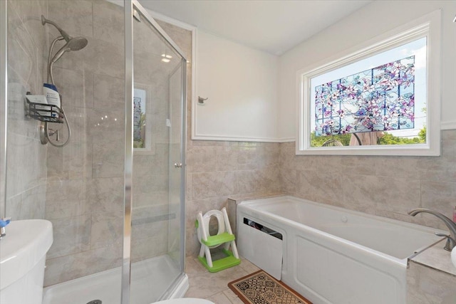 10067 W Logan Ct, Zion, IL 60099 - bathroom featuring a bath, a shower stall, tile walls, and tile patterned floors