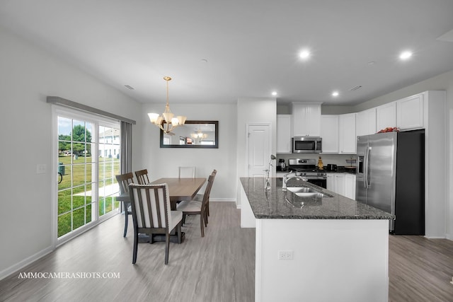 3376 Helene Rieder Dr, Montgomery, IL 60538 - kitchen featuring appliances with stainless steel finishes, a chandelier, light wood-style floors, dark stone countertops, and white cabinets