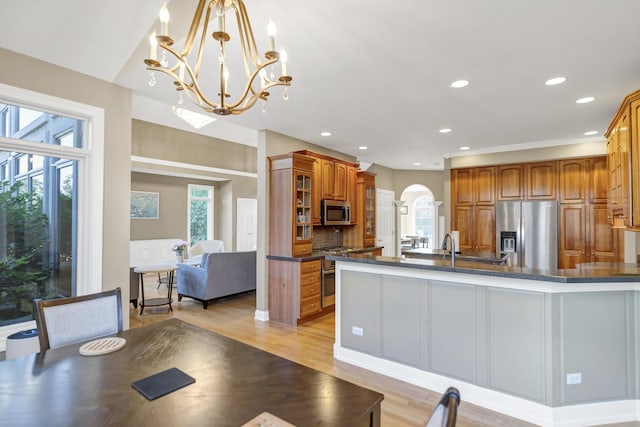 1123 Chadwick Ct, Aurora, IL 60502 - kitchen with appliances with stainless steel finishes, arched walkways, brown cabinetry, a chandelier, and light wood-type flooring
