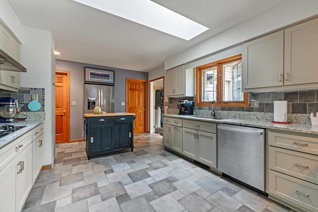 3063 Wedgewood Dr, Dekalb, IL 60115 - kitchen with appliances with stainless steel finishes, a skylight, decorative backsplash, stone finish floors, and wall chimney exhaust hood