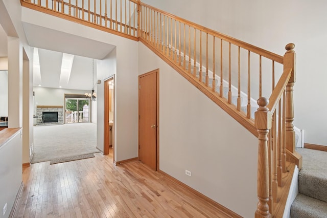 11636 Waterway Ct, Orland Park, IL 60467 - staircase featuring hardwood / wood-style floors, a stone fireplace, a chandelier, carpet floors, and a high ceiling