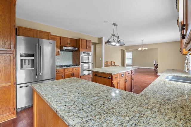 739 Crest Ave, Schaumburg, IL 60193 - kitchen featuring appliances with stainless steel finishes, under cabinet range hood, dark wood-style floors, a kitchen island, and brown cabinetry