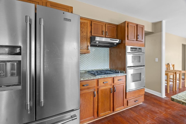 739 Crest Ave, Schaumburg, IL 60193 - kitchen with appliances with stainless steel finishes, under cabinet range hood, dark wood-style flooring, decorative backsplash, and brown cabinetry