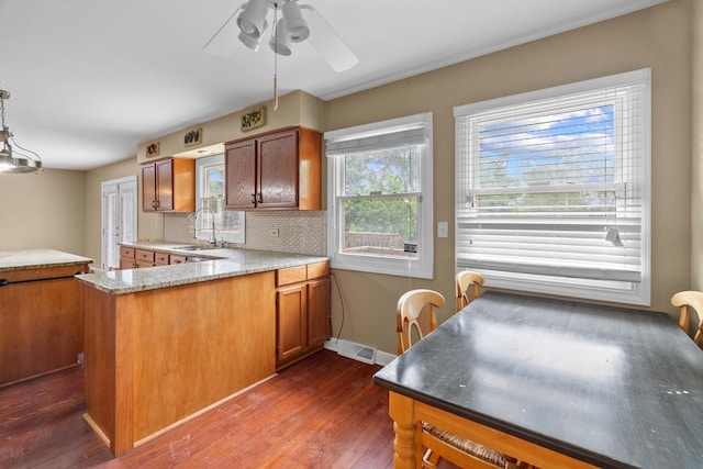 739 Crest Ave, Schaumburg, IL 60193 - kitchen with dark wood-type flooring, brown cabinetry, a ceiling fan, backsplash, and a peninsula