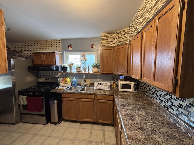 5409 S Richmond St, Chicago, IL 60632 - kitchen featuring stainless steel range with gas cooktop, white microwave, under cabinet range hood, brown cabinets, and dark countertops