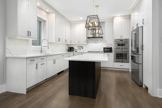 2441 N Clybourn Ave Unit 1, Chicago, IL 60614 - kitchen with appliances with stainless steel finishes, a kitchen island, dark wood-type flooring, backsplash, and white cabinetry