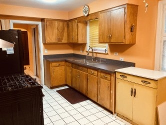 5547 N California Ave, Chicago, IL 60625 - kitchen with brown cabinets, dark countertops, light tile patterned flooring, and freestanding refrigerator