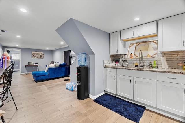 11030 S Ave L, Chicago, IL 60617 - kitchen featuring white cabinetry, light stone counters, decorative backsplash, light wood-style floors, and open floor plan