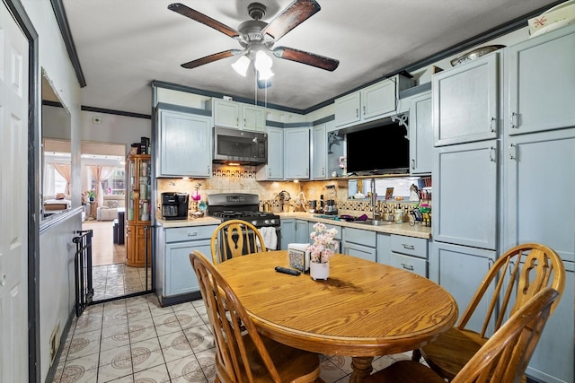 11030 S Ave L, Chicago, IL 60617 - kitchen featuring stainless steel microwave, range with gas stovetop, ceiling fan, light countertops, and decorative backsplash