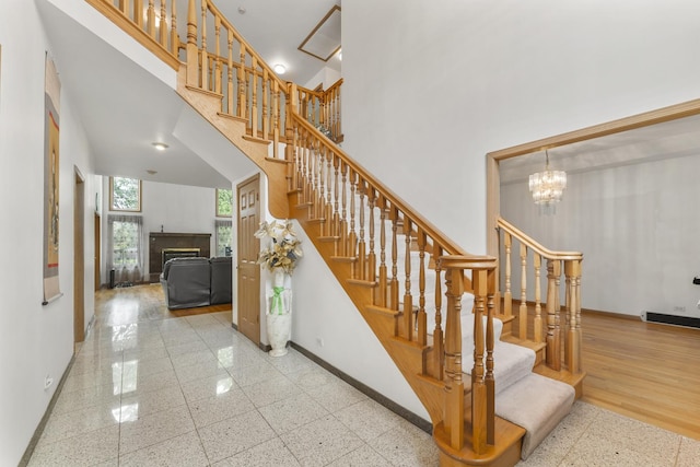 1007 Wildwood Ln, Mount Prospect, IL 60056 - staircase with a towering ceiling, a tiled fireplace, and a chandelier