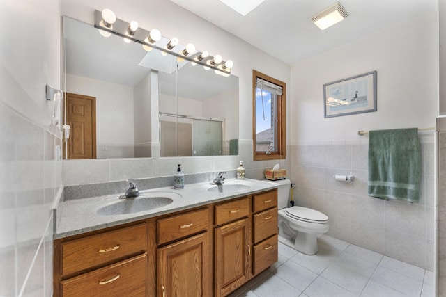 1007 Wildwood Ln, Mount Prospect, IL 60056 - bathroom with tile walls, double vanity, tile patterned flooring, a stall shower, and a wainscoted wall