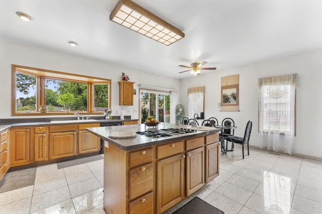 1007 Wildwood Ln, Mount Prospect, IL 60056 - kitchen featuring gas cooktop, dishwashing machine, a kitchen island, a ceiling fan, and brown cabinetry