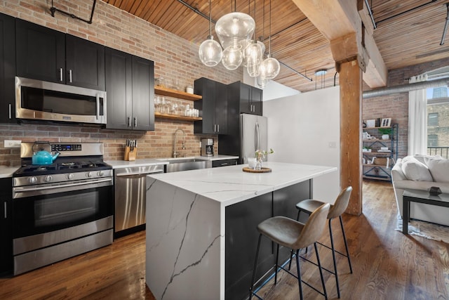 550 N Kingsbury St Unit 515, Chicago, IL 60654 - kitchen with appliances with stainless steel finishes, a wooden ceiling with exposed beams, brick wall, a center island, and dark cabinets