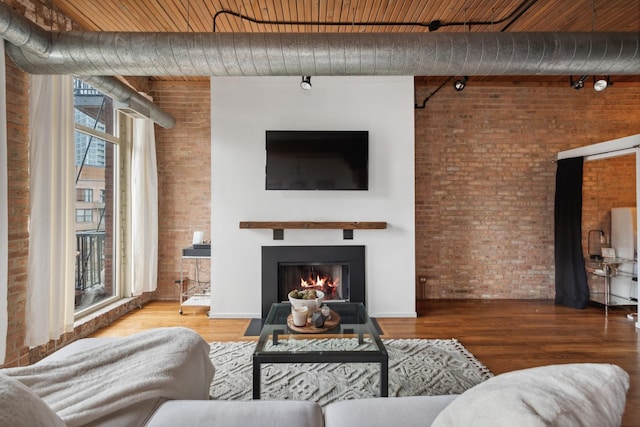 550 N Kingsbury St Unit 515, Chicago, IL 60654 - living area featuring brick wall, a lit fireplace, wood finished floors, and rail lighting