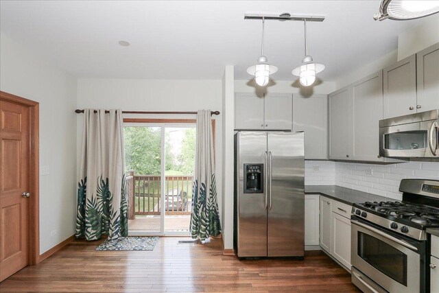 1137 N Claremont Dr, Palatine, IL 60074 - kitchen with appliances with stainless steel finishes, dark countertops, decorative backsplash, dark wood-style floors, and hanging light fixtures
