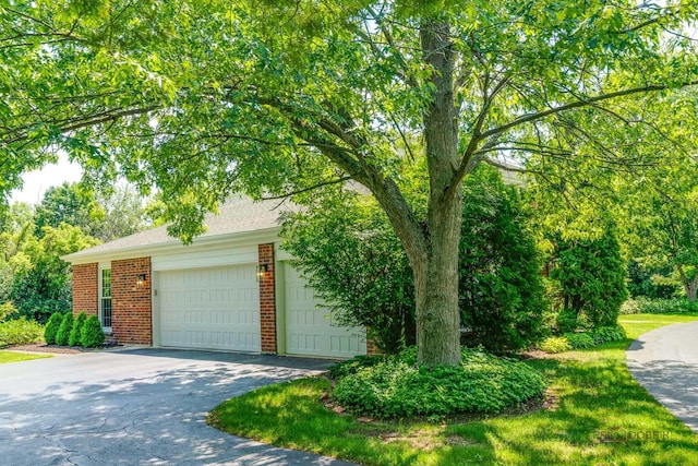 555 W Everett Rd, Lake Forest, IL 60045 - view of property hidden behind natural elements with brick siding, asphalt driveway, and an attached garage