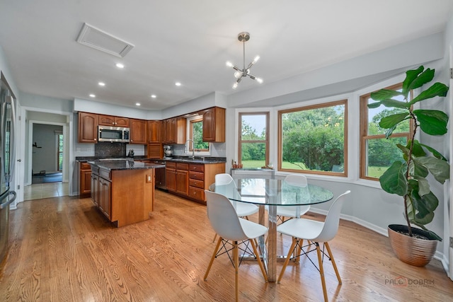 555 W Everett Rd, Lake Forest, IL 60045 - kitchen with stainless steel appliances, a kitchen island, dark countertops, brown cabinets, and light wood-type flooring