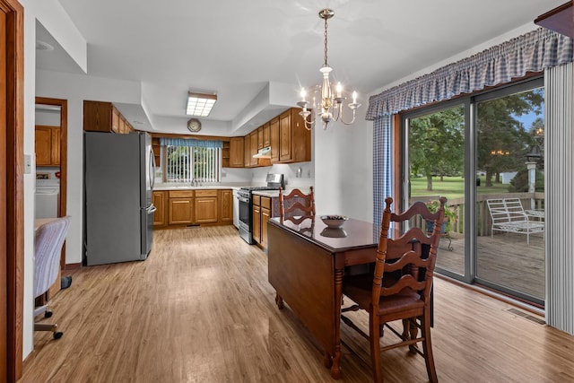 23201 Norma Ln, Harvard, IL 60033 - kitchen with appliances with stainless steel finishes, a chandelier, light wood-style flooring, and washer / dryer