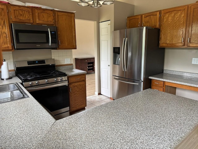 2404 Kenmore Ct, Schaumburg, IL 60193 - kitchen featuring appliances with stainless steel finishes, brown cabinets, decorative backsplash, and light tile patterned flooring