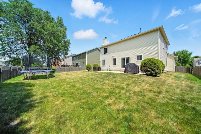 2942 Heather Ln, Montgomery, IL 60538 - rear view of house with a trampoline, a fenced backyard, and a chimney