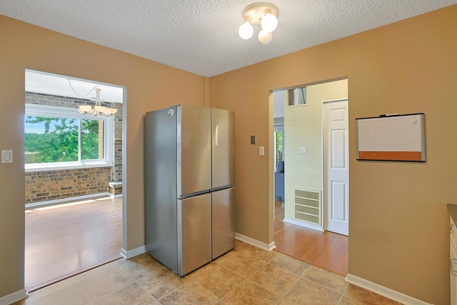 1501 Woodbridge Rd Unit 3E, Joliet, IL 60436 - kitchen with freestanding refrigerator, a textured ceiling, a chandelier, and light tile patterned floors