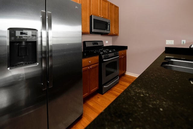 1151 W 15th St Unit 336, Chicago, IL 60608 - kitchen featuring stainless steel appliances, light wood-type flooring, dark stone countertops, and brown cabinets