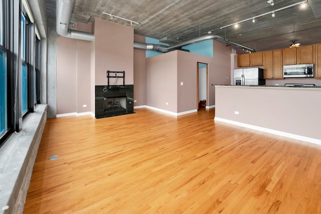 1151 W 15th St Unit 336, Chicago, IL 60608 - unfurnished living room featuring rail lighting, light wood-type flooring, a tile fireplace, and a towering ceiling
