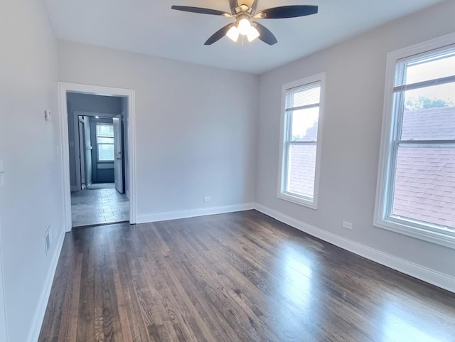 spare room with plenty of natural light, dark wood finished floors, and a ceiling fan