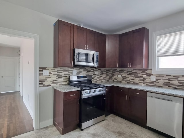 kitchen featuring stainless steel appliances, light stone countertops, and tasteful backsplash