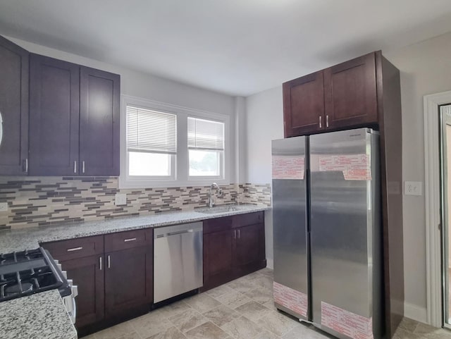 kitchen featuring appliances with stainless steel finishes, backsplash, and light stone counters