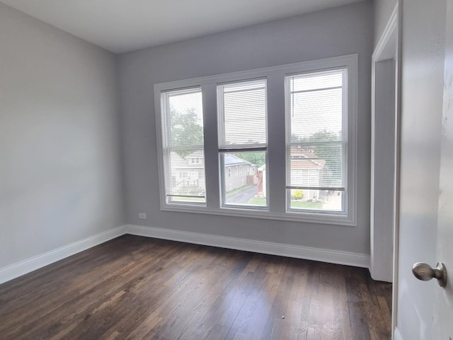 spare room with baseboards and dark wood-style floors