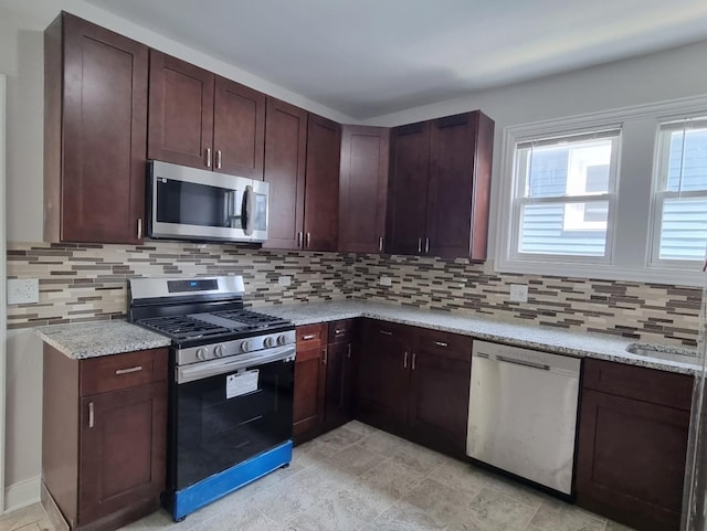 kitchen featuring stainless steel appliances, tasteful backsplash, and light stone countertops