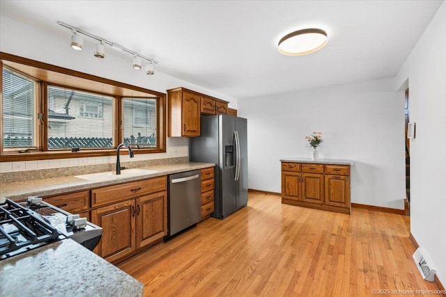 4616 W 105th Pl, Oak Lawn, IL 60453 - kitchen with stainless steel appliances, brown cabinets, light wood finished floors, and rail lighting