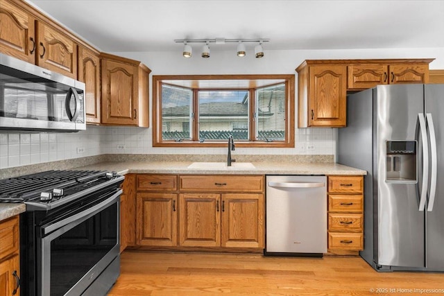 4616 W 105th Pl, Oak Lawn, IL 60453 - kitchen with appliances with stainless steel finishes, brown cabinetry, tasteful backsplash, light wood finished floors, and light countertops