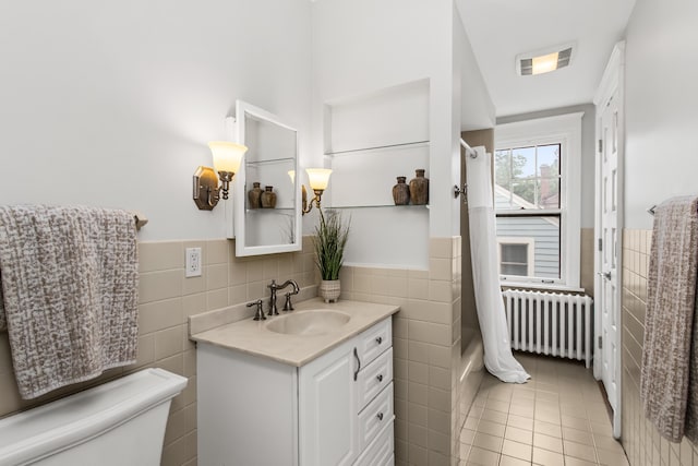 2423 Harrison St, Evanston, IL 60201 - full bathroom with tile walls, radiator, vanity, a wainscoted wall, and tile patterned flooring