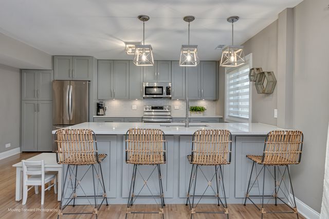 1906 Heatherway Ln Unit 7, New Lenox, IL 60451 - kitchen featuring stainless steel appliances, gray cabinetry, light wood-style flooring, backsplash, and light countertops