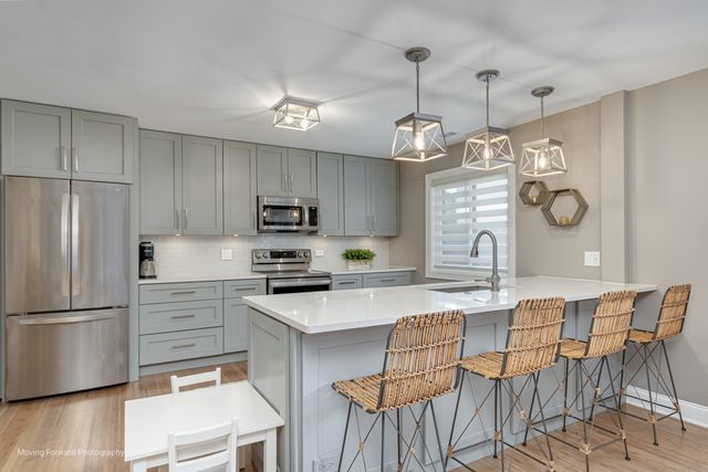1906 Heatherway Ln Unit 7, New Lenox, IL 60451 - kitchen with stainless steel appliances, gray cabinetry, a kitchen bar, and light wood finished floors