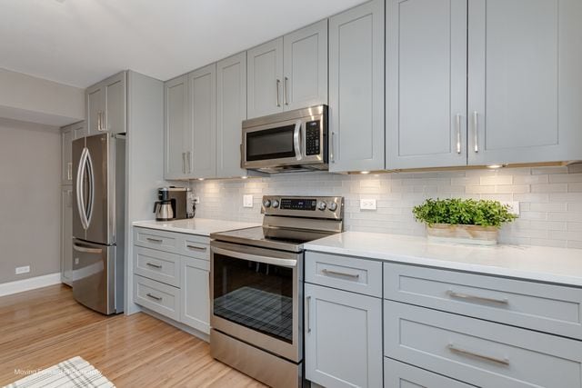 1906 Heatherway Ln Unit 7, New Lenox, IL 60451 - kitchen with appliances with stainless steel finishes, gray cabinetry, light wood-style floors, and light countertops