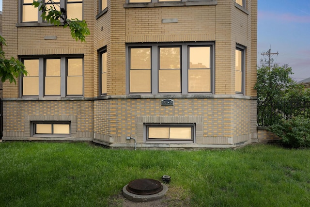 5609 N Mango Ave Unit 1W, Chicago, IL 60646 - back of property at dusk featuring brick siding, a yard, and a fire pit