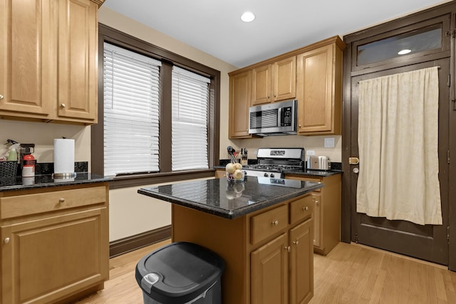 5609 N Mango Ave Unit 1W, Chicago, IL 60646 - kitchen with stainless steel appliances, light wood-type flooring, a kitchen island, dark stone counters, and recessed lighting