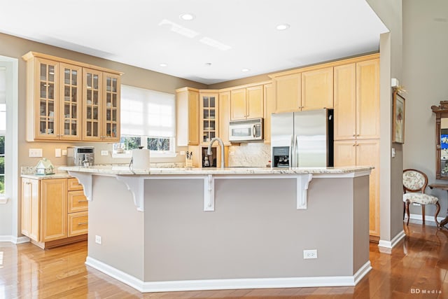 18011 Breckenridge Blvd, Orland Park, IL 60467 - kitchen featuring stainless steel fridge with ice dispenser, light wood-style flooring, a kitchen bar, light stone counters, and recessed lighting