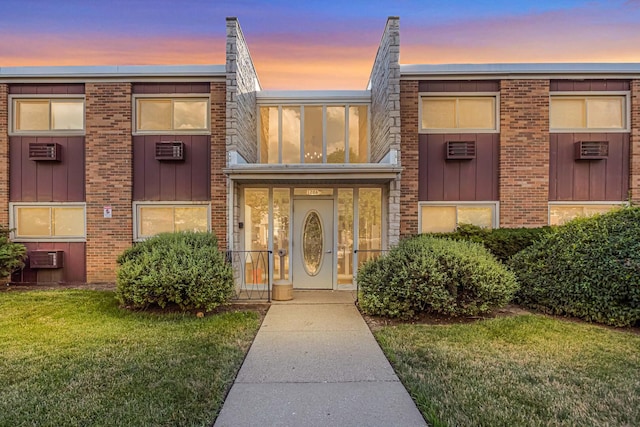 120A Collen Dr Unit 105, Lombard, IL 60148 - view of front facade with board and batten siding, a yard, brick siding, a wall mounted AC, and a wall unit AC