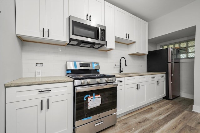 14137 Greenwood Rd, Dolton, IL 60419 - kitchen with stainless steel appliances, white cabinetry, light wood-type flooring, light stone counters, and tasteful backsplash