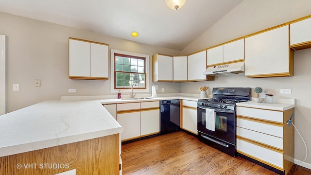kitchen with black appliances, under cabinet range hood, lofted ceiling, light wood-style floors, and white cabinetry