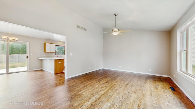 unfurnished living room featuring a chandelier, wood finished floors, ceiling fan, and lofted ceiling