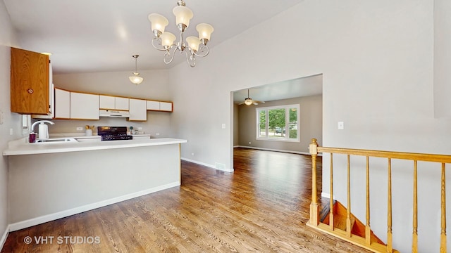 kitchen featuring vaulted ceiling, wood finished floors, range, light countertops, and a peninsula