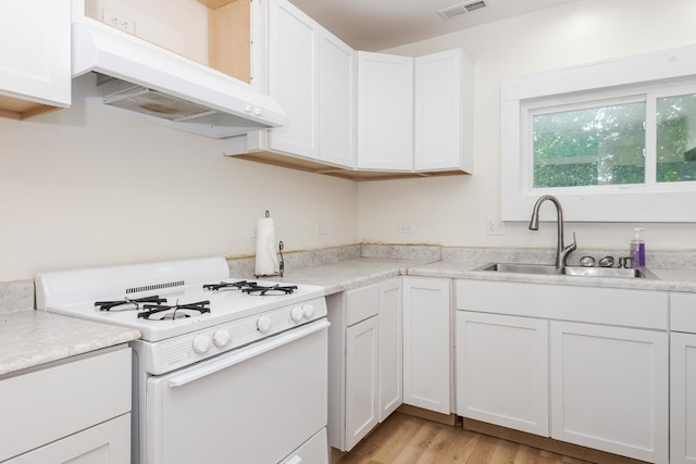 411 E Mazon St, Gardner, IL 60424 - kitchen featuring white gas range oven, under cabinet range hood, white cabinets, light countertops, and light wood-type flooring