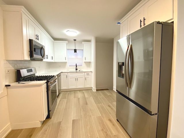 kitchen featuring stainless steel appliances, light wood-style floors, white cabinetry, and light countertops