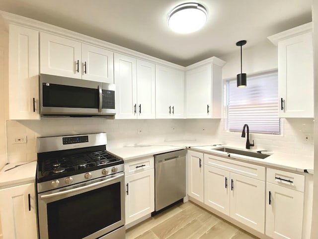 kitchen featuring stainless steel appliances, white cabinets, light countertops, tasteful backsplash, and hanging light fixtures