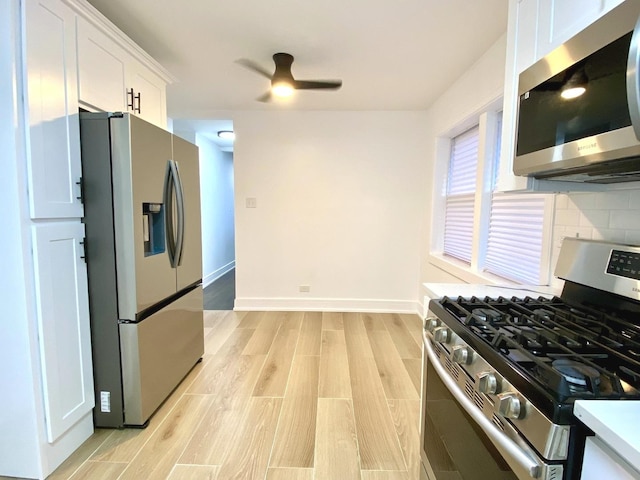 kitchen with appliances with stainless steel finishes, white cabinetry, light wood-style flooring, backsplash, and a ceiling fan
